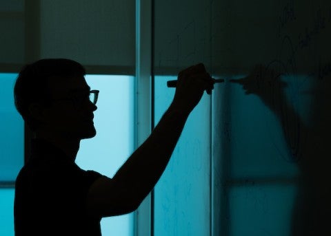 Student writing on a white board.
